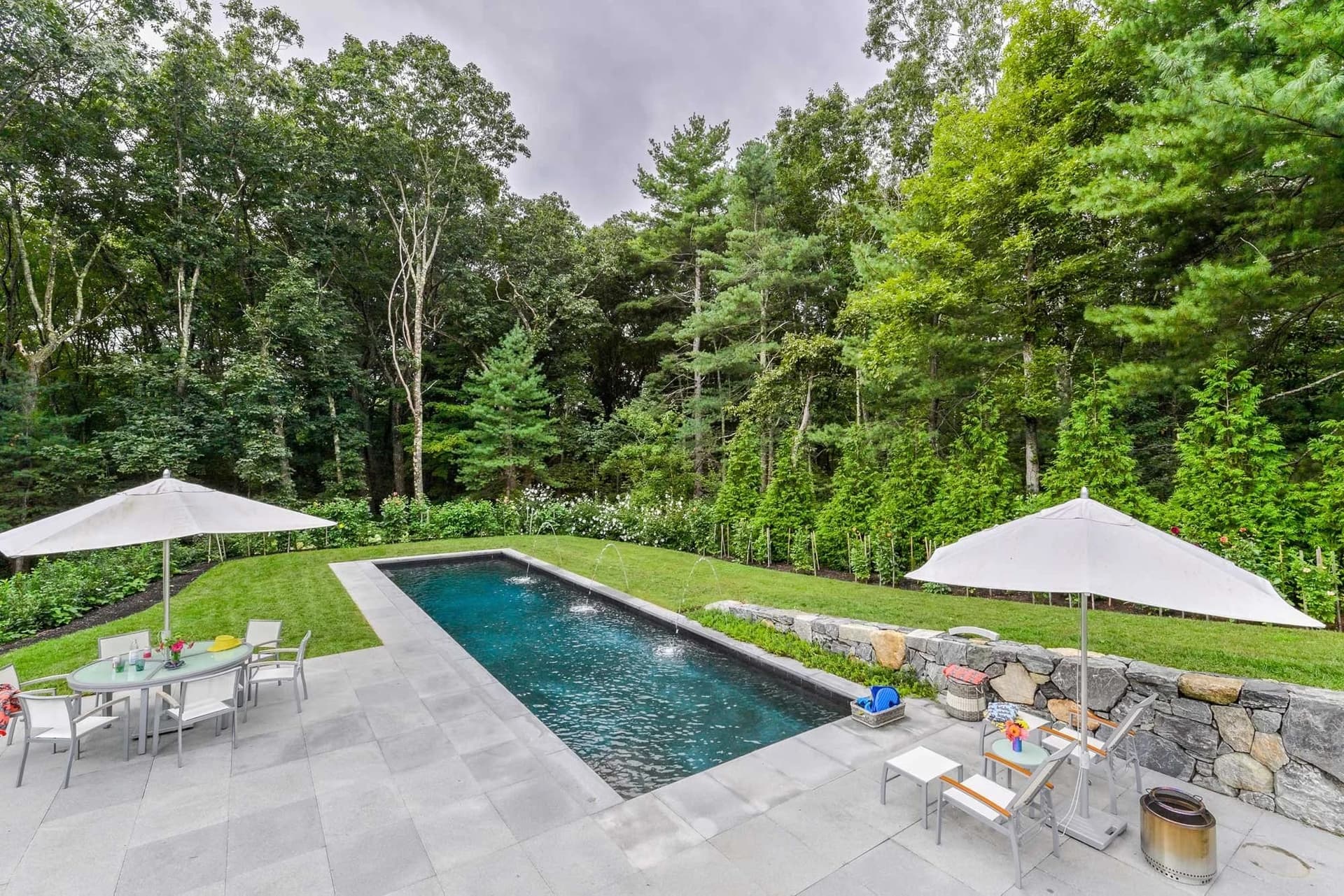 Bluestone pool terrace with a fieldstone retaining wall in Lincoln, MA